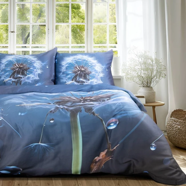 Pościel satyna bawełniana 160x200 Satynlove Premium w granatowym kolorze z motywem dmuchawca, leżąca na łóżku. Zestaw obejmuje poszewki na poduszki oraz kołdrę, z widocznymi detalami wzoru i faktury. Tło jasne, z oknem.