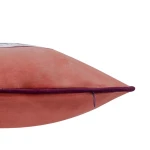 Poszewka dekoracyjna 43x43 w pudrowym różu, wykończona fioletowym obszyciem. Widok z boku, ukazuje kształt trójkątny produktu. Tekstura materiału jest gładka. Dodatkowy szczegół to zamek, który jest widoczny w dolnej części poszewki.