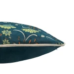 Poszewka dekoracyjna w rozmiarze 43x43 cm z zielonym roślinnym wzorem, leżąca na boku. Materiał ma delikatną teksturę, a na brzegach ozdobne obszycie. Wzór przedstawia kwiaty w odcieniach zieleni i pomarańczy na tle w kolorze niebieskim.