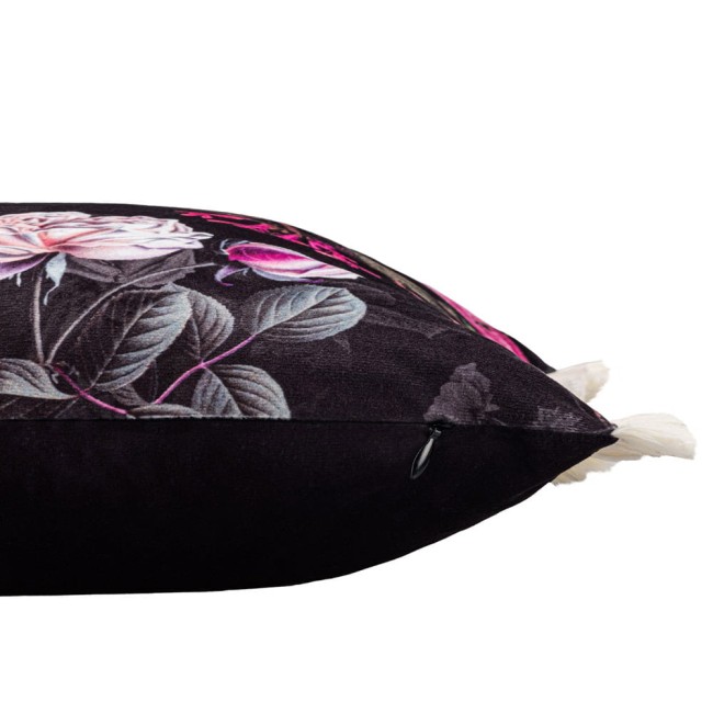 Poszewka dekoracyjna 43x43 cm w ciemnym kolorze z fioletowymi kwiatami, leżąca na boku. Ozdobiona frędzlami oraz subtelnym zapięciem; do materiału doda je delikatna tekstura. Tło jednolite, co podkreśla wzór.