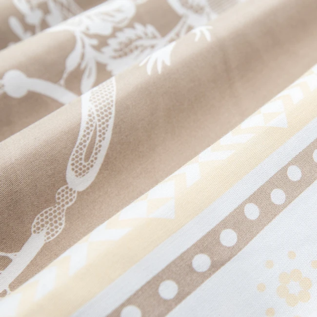 Pościel satyna bawełniana 160x200 Satynlove w kolorze białym z beżowymi kwiatami, ukazana w zbliżeniu. Widoczne wzory kwiatowe oraz faktura materiału. Produkt leży na gładkim tle, ukazując detale tkaniny.