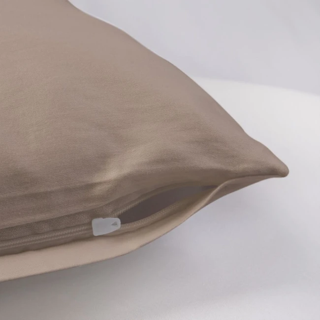 Poszewka satynowa 50x70 w kolorze ciemnego beżu, leżąca na białym tle, z widocznym suwakiem. Gładka, teksturowana powierzchnia podkreśla elegancję materiału. Kształt prostokątny, idealna do dekoracji poduszek w sypialni lub salonie.