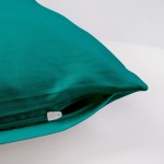 Poszewka satynowa 50x70 w kolorze ciemnego turkusu, leżąca na jednolitym tle. Zamek błyskawiczny widoczny w dolnej części poszewki, gładka faktura materiału. Idealna do dekoracji poduszek w sypialni lub salonie.