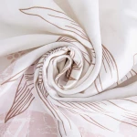 Pościel satyna bawełniana 220x200 w białym kolorze z różowymi, delikatnymi kwiatami. Złożona w spirale, ukazująca gładką teksturę materiału. Wzór roślinny nadrukowany na całości, bez widocznych napisów lub logo, na jasnym tle.