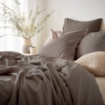 Poszewka satynowa 50x70 w kolorze sepia leży na łóżku, obok niej znajdują się dwa poduszki. Tkanina ma gładką, błyszczącą fakturę. W tle widoczne są delikatne rośliny oraz filiżanka, co tworzy przytulną aranżację.