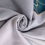 Satynowa pościel w kolorze szarym, zwinięta w roladę, z zielonymi liśćmi na widocznej krawędzi. Materiał o gładkiej teksturze, zasłaniający szczegóły wzoru. Zestaw przeznaczony do łóżka o wymiarach 140x200 cm.