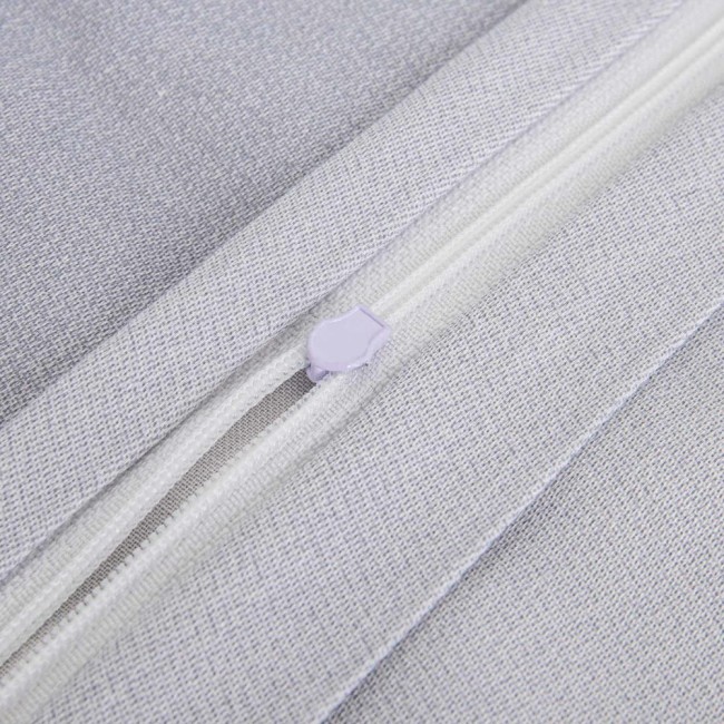 Zbliżenie na zamek błyskawiczny w pościeli satynowej w kolorze szarym z drobnym wzorem tkaniny. Widoczne jest zamknięcie w białym kolorze z fioletowym uchwytem. Produkt ukazany w pozycji leżącej, na jednolitym tle.