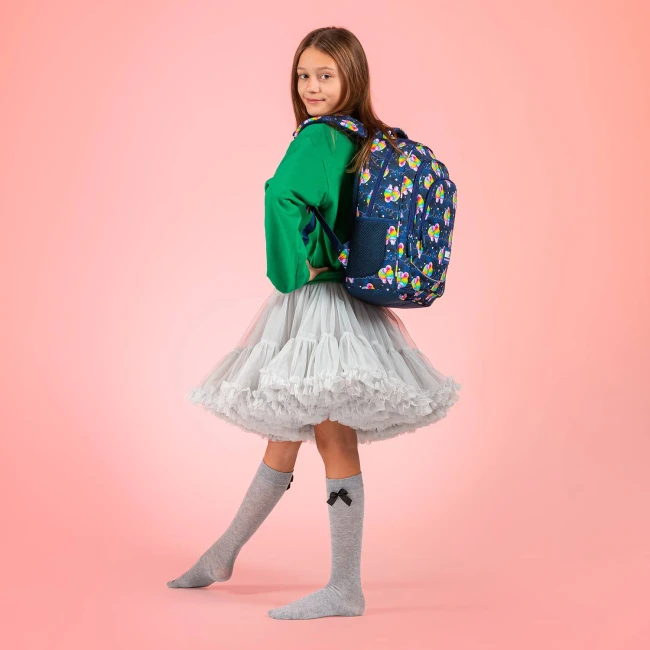 Plecak szkolny BackUp Papugi w granatowym kolorze z wzorem kolorowych papug. Został noszony na plecach przez dziewczynkę w zielonej bluzie i tiulowej spódnicy.