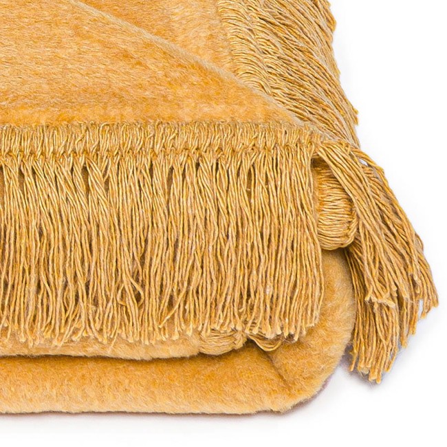 Koc bawełniany 150x200 w kolorze miodowym, z frędzlami na krótszym brzegu, złożony w poziomie. Tekstura miękka i gęsta, doskonały do użycia w domowych aranżacjach. Idealny jako element dekoracyjny lub dodatkowe okrycie na chłodne wieczory.