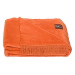Koc bawełniany 150x200 w pomarańczowym kolorze, z frędzlami na krótszym boku. Złożony, leżący na płaskiej powierzchni, na jasnym tle. Wygląd teksturowany, bez widocznych napisów lub logo. Idealny do użytku w pomieszczeniach oraz na piknikach.