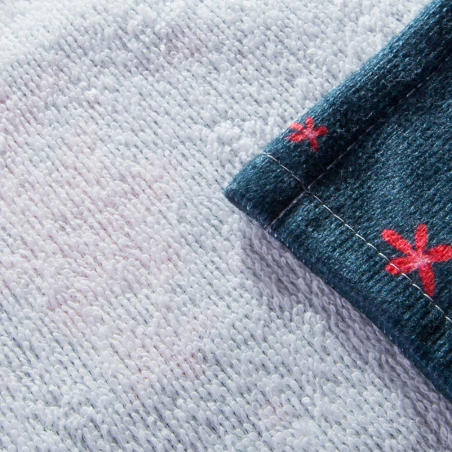 Ścierka kuchenna Christmas, w zestawie 2 sztuki, w kolorze białym z wzorem Świętego Mikołaja i czerwonymi reniferami. Ułożona w zbliżeniu, z widocznymi detalami haftu na krawędzi. Materiał tekstylny, przyjemny w dotyku, idealny do dekoracji świątecznej.