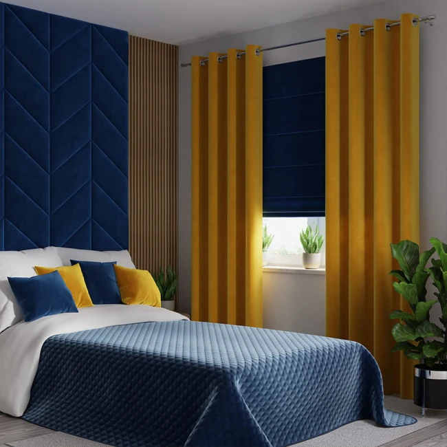 Zasłona welwetowa w kolorze szafranowym, rozłożona na oknie, wkomponowana w nowoczesną aranżację sypialni. Szerokość 140 cm, długość 260 cm, mocowana na przelotkach. W tle niebieska ściana z fakturą oraz roślinność na parapecie.