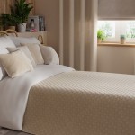 Poszewka welwetowa 40x40 w kolorze jasno beżowym, z delikatną fakturą, leży na łóżku z białą pościelą. Z przodu widoczne okrągłe poduszki w odcieniu beżowym. Tło z jasnymi zasłonami i roślinami. Zbliżenie na teksturę materiału.