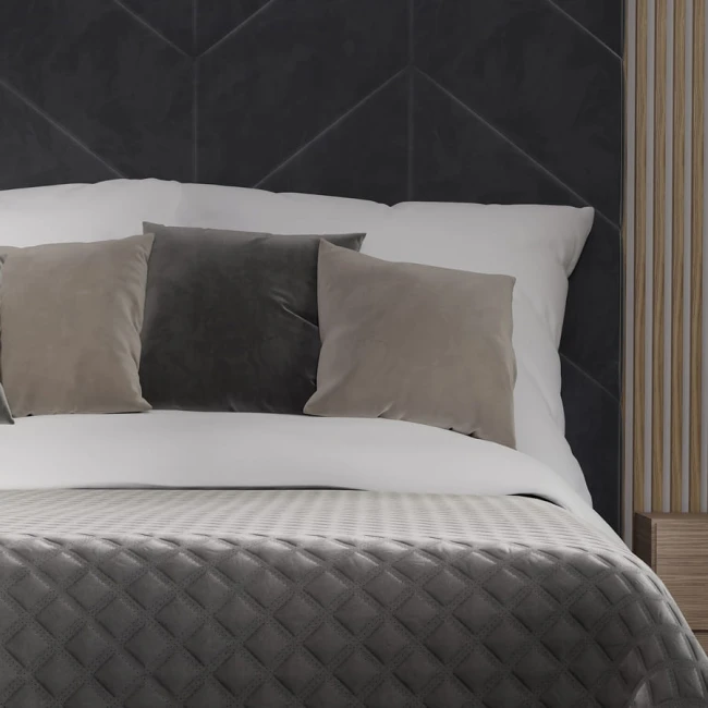 Poszewka welwetowa 40x40 w kolorze ciemno szarym, umieszczona na łóżku, z miękkim, teksturowanym wykończeniem.