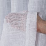 Firana na przelotkach typu len, gładka, w kolorze białym z etaminy, o wymiarach 140x250 cm. Zbliżenie na fakturę materiału, ukazujące delikatną, przejrzystą strukturę. Produkt leży na dłoni, co podkreśla jego lekkość i zwiewność.