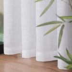 Firana na przelotkach w kolorze białym, wykonana z etaminy, o wymiarach 140x250 cm. Tkanina ma delikatną fakturę i jest lekko przezroczysta. Ujęcie z boku, z widocznym dolnym wykończeniem. W tle liście rośliny na drewnianej podłodze.