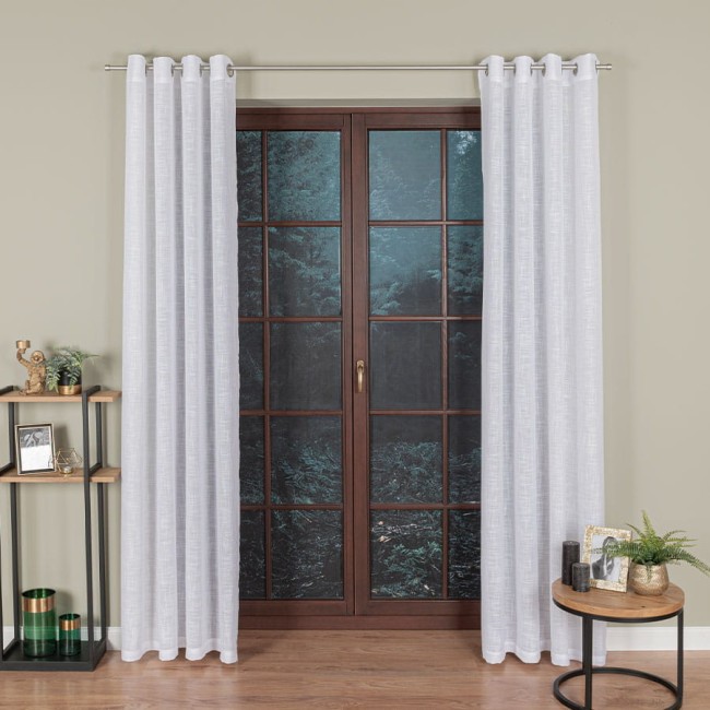 Firana na przelotkach w kolorze białym, wykonana z etaminy, o wymiarach 140x250 cm. Zawieszona na metalowej karniszu, z delikatną fakturą, w aranżacji przy oknie z drewnianą ramą.