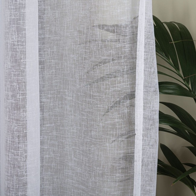 Firana na przelotkach w kolorze białym, wykonana z etaminy, o wymiarach 140x250 cm. Stoi w pionie, z widoczną teksturą materiału. W tle pojawia się liść rośliny, co podkreśla aranżację wnętrza.