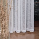 Firana na przelotkach w kolorze białym, wykonana z etaminy, o wymiarach 140x250 cm. Zawieszona w prosty sposób, z widoczną fakturą tkaniny. W tle dekoracyjny wazon z suchymi gałązkami, na drewnianej podłodze.
