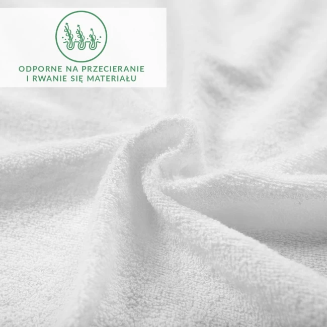 Prześcieradło frotte z gumką 140x200, wykonane z białego materiału. Ujęcie z bliska, pokazujące fakturę tkaniny. Widoczny nadruk informujący o odporności na przecieranie i rwanie materiału. Produkt leży, rozłożony na tle o jednolitym kolorze.