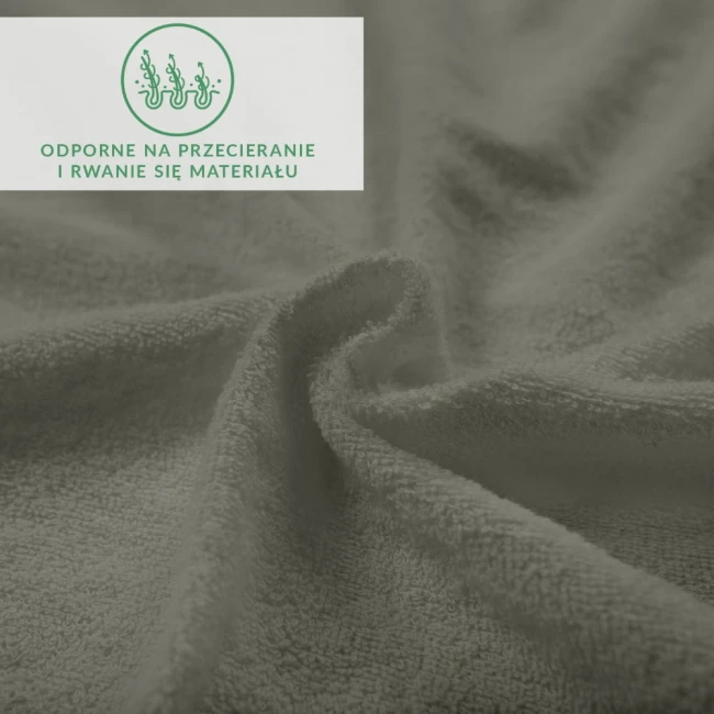 Frotte prześcieradło z gumką w kolorze szarym, matowe, o fakturze pluszowej. Produkt leży na płasko, z widocznymi delikatnymi włóknami materiału. Na zdjęciu znajduje się zielony napis informujący o odporności na przecieranie.