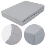 Prześcieradło jersey z gumką 90x200 w kolorze popielatym leży na białym tle. Przedstawia gładką fakturę materiału. Zbliżenie na brzeg pokazuje gumkę oraz detal szwu, a także ścięty róg. Produkt jest rozłożony, gotowy do użytku.