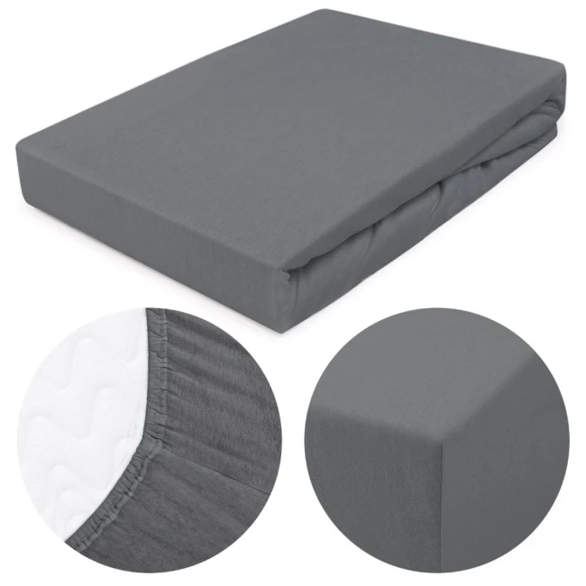 Prześcieradło jersey z gumką w kolorze szarym, rozmiar 180x200 cm. Produkt leży poziomo, z widoczną teksturą materiału. Ujęcie z bliska pokazuje detale gumki oraz narożniki, które dopasowują się do materaca. Brak widocznych napisów lub logo.