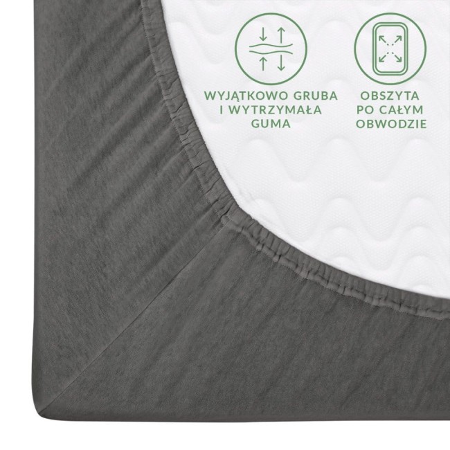 Prześcieradło jersey z gumką w kolorze szarym, o wymiarach 160x200 cm. Widoczna gruba guma obszyta po całym obwodzie, materiał gładki i elastyczny, idealne do użytku na materacach. Ujęcie z boku, zbliżenie na detal.