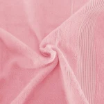 Ręcznik bambusowy 70x140 cm w kolorze różowym. Miękka, teksturowana powierzchnia z subtelnym wzorem na brzegach. Leży w naturalnym, lekko zmiętym ułożeniu, podkreślając swoją elastyczność i komfort.