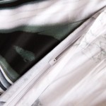 Pościel satyna bawełniana 220x200 w szaro-beżową abstrakcję. Zamek błyskawiczny widoczny na krawędzi poszewki. Materiał gładki, z delikatnym wzorem, stonowane kolory. Produkt leży płasko, ukazując detale tkaniny i wykończenia.