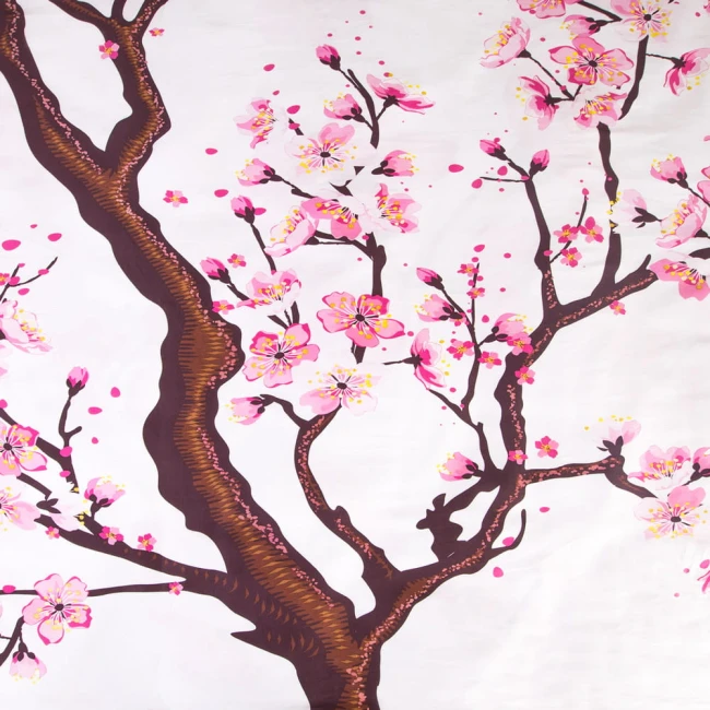Pościel satyna bawełniana 180x200 w kolorze białym z nadrukiem gałęzi drzewa wiśniowego. Wzór z różowymi kwiatami i brązowym pniem, widoczny w zbliżeniu, na gładkim tle.