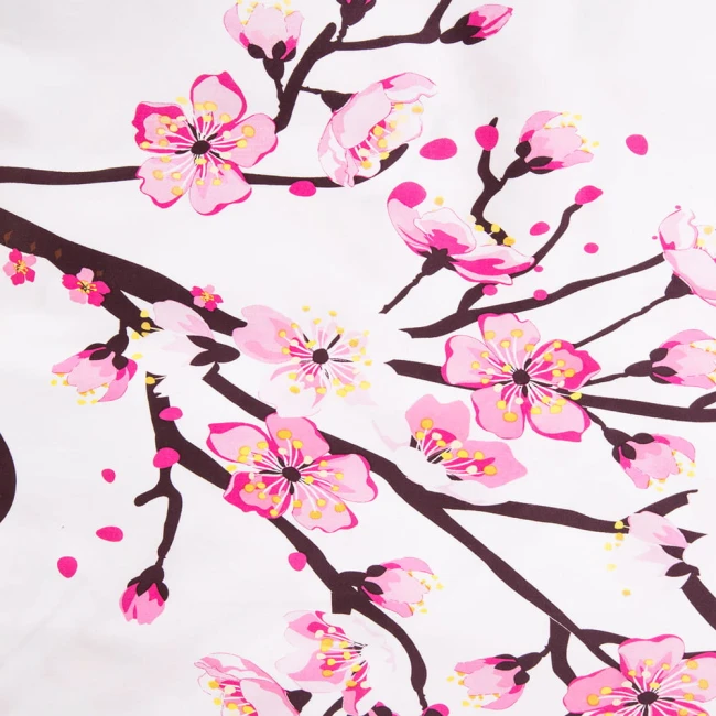 Pościel satyna bawełniana 180x200 z białym tłem, zdobiona różowymi kwiatami wiśni. Wzór pokazuje gałęzie z kwiatami i pąkami. Materiał jest gładki i lśniący. Produkt leży na płaskiej powierzchni, ukazując detale wzornictwa.