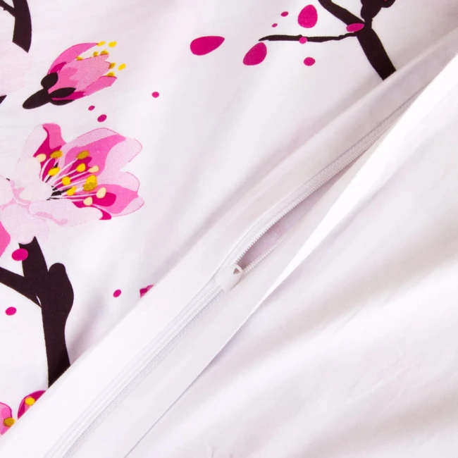 Pościel satynowa 180x200 z białym tłem, na której widoczne kwiaty wiśni w odcieniach różu i czerni. Zamek błyskawiczny widoczny na boku poszwy. Produkt leży na płasko, ukazując detale wzoru i fakturę materiału.