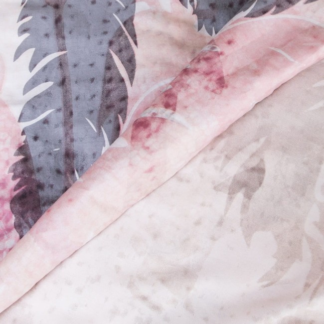 Pościel satyna bawełniana 220x200 w fioletowo-różowym kolorze z motywem łapacza snów. Widoczne delikatne wzory na tkaninie, materiał o gładkiej fakturze, złożony w połowie, ukazujący różne odcienie.