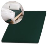 Prześcieradło satynowe bez gumki w kolorze butelkowej zieleni, rozłożone, leżące na łóżku z jasnymi poduszkami i białą narzutą, wykonane z gładkiego materiału. Widoczny detal tekstury satyny oraz rozmiar 160x220 cm.