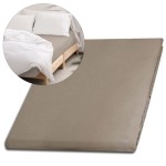 Prześcieradło satynowe bez gumki o wymiarach 160x220 cm w kolorze ciemnego beżu, leżące na płaskiej powierzchni. W tle widoczny jest fragment łóżka z białymi poduszkami i narzutą. Faktura materiału gładka i błyszcząca.