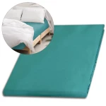 Prześcieradło satynowe bez gumki w kolorze ciemnego turkusu o wymiarach 200x220 cm. Produkt leży płasko, prezentując gładką fakturę. W tle widoczna część łóżka z białą pościelą i poduszkami.