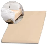 Prześcieradło satynowe bez gumki w kolorze jasnego beżu, w rozmiarze 200x220 cm. Widoczne na zdjęciu leży na łóżku, obok poduszki i narzuty. Gładka faktura materiału, prostokątny kształt, brak dodatkowych dekoracji.