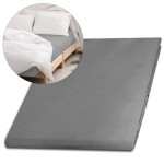 Prześcieradło satynowe bez gumki w kolorze popielatym, w rozmiarze 200x220 cm, leżące na łóżku. Produkt przedstawiony z boku, w aranżacji z białymi poduszkami i narzutą, na drewnianej ramie łóżka. Tło w jasnych odcieniach, neutralne i minimalistyczne.