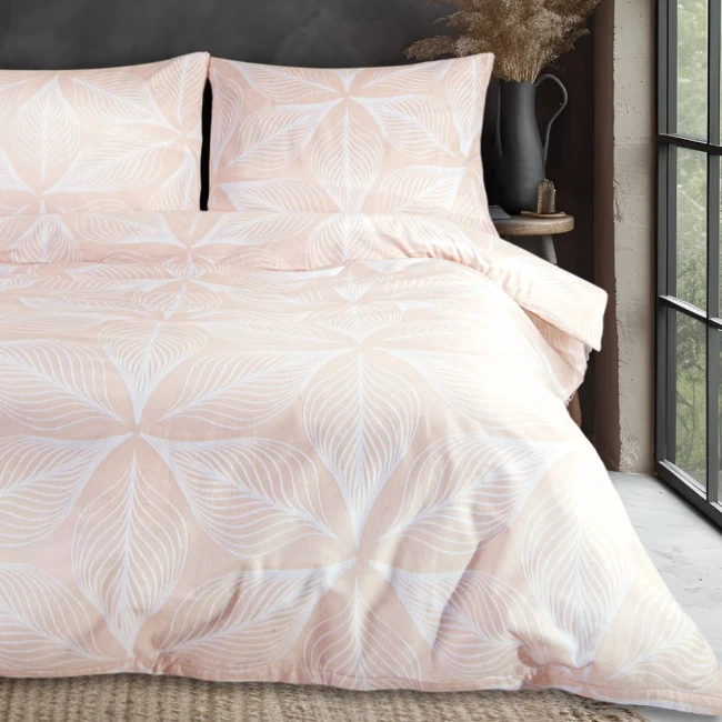 Pościel flanelowa w rozmiarze 160x200 cm w kolorze pudrowego różu z białym wzorem liści. Złożona narzuta na łóżku z poduszkami w tym samym stylu, prezentująca delikatny, kwiatowy motyw. Tło neutralne, w stylowym wnętrzu.