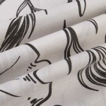 Pościel satyna bawełniana 160x200 w białym kolorze z czarnymi konturowymi kwiatami i liśćmi, złożona w sposób ukazujący detale wzoru i tekstury materiału. Ujęcie w zbliżeniu, ukazujące delikatność wykończenia i fakturę tkaniny.