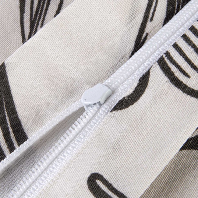 Zbliżenie na zamek błyskawiczny widoczny na pościeli z satyny bawełnianej w białe i czarne konturowe kwiaty. Zamek jest biały, umieszczony na krawędzi poszewki, co umożliwia łatwe zakładanie. Tło zdjęcia jest jasne, co podkreśla detale materiału.