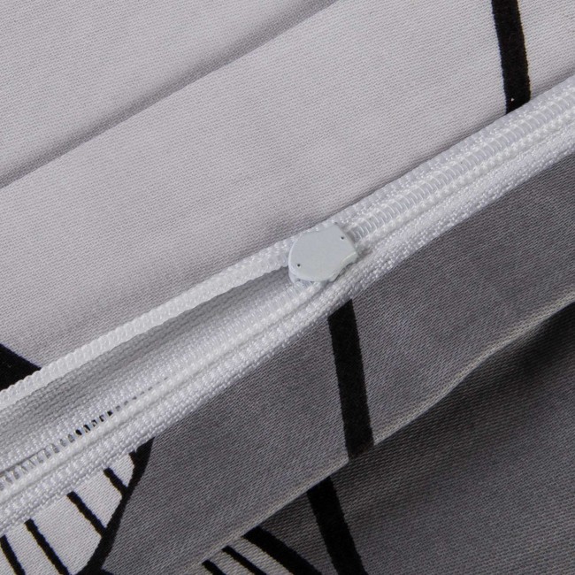 Zbliżenie na zamek błyskawiczny pościeli satynowej bawełnianej 200x220 cm w kolorze białym z czarno-białymi liśćmi miłorzębu. Widoczna jest faktura materiału oraz detale wykończenia. Pościel ma matowy wygląd i elegancki wzór roślinny.