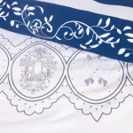 Pościel satyna bawełniana 220x200 w kolorze granatowym z białymi pasami, zdobiona ornamentami. Produkt leży, ukazując wzory w dekoracyjnych obramieniach oraz ozdobne detale. Tło jest neutralne, co podkreśla design pościeli.