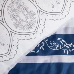 Pościel satynowa 220x200 cm w granatowo-białe pasy oraz ornamenty. Ujęcie z góry, zestawione dwa wzory: górna część z delikatnym wzorem lidowym na jasnym tle, dolna część w pionowe pasy z eleganckim zdobieniem. Mam gwarantuje komfort i estetykę.