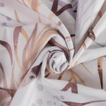 Pościel satynowa 160x200 cm w kolorze białym z szaro-beżowymi liśćmi. Materiał gładki, z delikatnym wzorem w odcieniach beżu i brązu, zwinięta w luźny sposób, ukazująca fakturę i szczegóły nadruku.