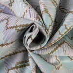 Pościel bawełniana satynowa 200x220 w błękitnym kolorze z szarym geometrycznym wzorem. Materiał gładki, z delikatnym połyskiem, zwinięty w kształt spirali, ukazujący detale wzoru i fakturę tkaniny.