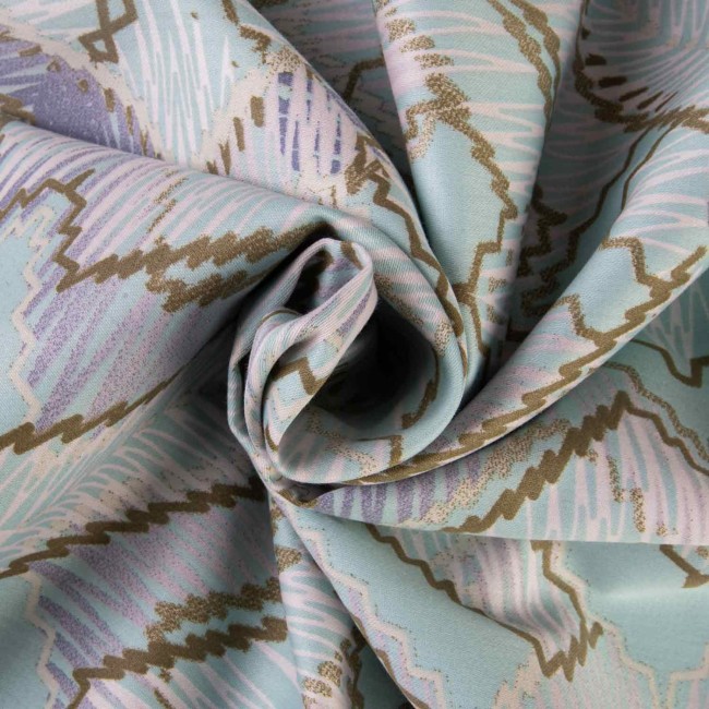 Pościel bawełniana satynowa 200x220 w błękitnym kolorze z szarym geometrycznym wzorem. Materiał gładki, z delikatnym połyskiem, zwinięty w kształt spirali, ukazujący detale wzoru i fakturę tkaniny.