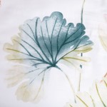 Pościel satynowa 220x200 w białym kolorze z delikatnym wzorem dużych, pastelowych liści w odcieniach zieleni i różu. Zbliżenie na liść w błękitnym odcieniu. Wzór na tle jest subtelny, co nadaje elegancki wygląd. Idealna do sypialni.