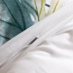 Pościel satyna bawełniana 220x200 cm w kolorze białym z pastelowymi liśćmi. Zamek błyskawiczny na poszewce. Widoczne detale tkaniny oraz wzór liści w odcieniach zieleni i żółci. Pościel z gładką fakturą, idealna do sypialni.